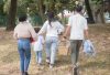 Family walking together carrying picnic basket in a sunny park.